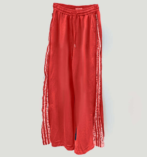 טרנינג בגוון אורנג' עם פסי תחרה לבנים ורוכסן בצידיו, עם גומי במותניים.